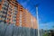 Suburban rustic back street unfinished building exterior facade fenced by metallic palisade perspective foreshortening in day