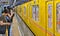 Subway station with yellow train and modern architecture with people waiting for train stop in Tokyo metro, Japan