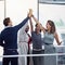 Succeeding as a team. a group of colleagues high fiving together in an office.