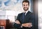 Success follows confidence. Cropped portrait of a handsome young businessman standing with his arms folded in the office