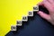 Success onboarding process symbol. Wood cubes stacking as step stair on yellow and black background, copy space. Businessman hand