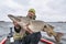 Success pike fishing. Happy fisherman with big fish trophy at boat