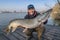 Success pike fishing. Happy fisherman with big fish trophy in hands