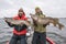 Success pike fishing. Happy two fishermen with big fish trophy at boat