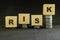 Success in risky investment and market volatility risk concept. Wooden blocks with coins and word risk on dark black background.