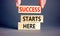 Success starts here symbol. Concept word Success starts here on beautiful wooden block. Businessman hand. Beautiful grey