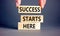 Success starts here symbol. Concept word Success starts here on beautiful wooden block. Businessman hand. Beautiful grey