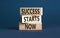 Success starts now symbol. Concept word Success starts now on beautiful wooden block. Beautiful grey table grey background.