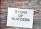 Success story typed on page and paper dollar signs around on wooden table. Career business concept