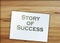 Success story typed on page and paper dollar signs around on wooden table. Career business concept