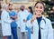 Success, thumbs up and portrait of a woman doctor with her team outdoor at the hospital. Leadership, smile and