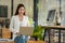 Successful Asian businesswoman sits at her desk at her laptop, smiling joyfully in the office.