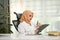 Successful Asian Muslim businesswoman reading and reviewing business report in her office
