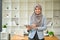 A successful Asian Muslim businesswoman stands in her office with a digital tablet in her hand