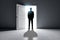 Successful business man standing in front of bright success door in concrete interior with shadow on floor. Future and dream