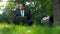 Successful businessman working with pleasure in park, sitting on grass, laptop