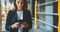 Successful businesswoman listens to financial news on her wireless headphones and checks email on smartphone during lunch break