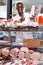 Successful butcher shop owner giving thumbs up, satisfied with quality of meat products