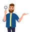 Successful cheerful bearded young man holding magnifying glass and gesturing hand sign to copy space side away to present.