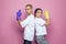 Successful cute couple woman and man wearing blue and yellow gloves on pink studio wall background, cleaning service