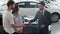 Successful deal between car salesman and young couple in car dealership.