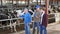 Successful elderly dairy farm owner with son and teen grandson posing together while working in stall with cows. Three