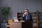 Successful elderly gray haired businessman in glasses and in suit working on laptop, talking on mobile phone