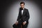 Successful elegant man in tuxedo and bowtie sitting on stool