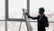 Successful expert businessman writes on flipchart standing in modern office with cityscape.