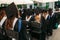 Successful graduates in academic dresses, at graduation, sitting