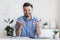 Successful handsome businessman sitting at desk in office, talking at camera