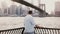 Successful happy businessman stands near Brooklyn Bridge embankment fence panorama in New York City, back view 4K.