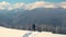 Successful hiker with backpack walking on snowy mountain hillside on cold winter day.