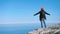 Successful hiker winner man celebrating victory standing on peak of cliff over blue sea