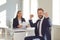 Successful interview. A man in a suit rejoices at a new job sitting at a table with a woman employer in a white office.