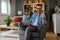 Successful male entrepreneur with wireless computer sitting on armchair and showing thumbs up sign. Young businessman laughing and