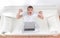 Successful man with arms up working on laptop at home