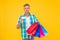 Successful mature shopper man carry shopping bags and hold business or credit card, bargain sale
