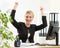 Successful middle-aged business woman holding arms up sitting at pc in office