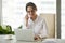 Successful millennial businesswoman using laptop talking on phon