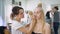 Successful, multi-beauty salon. Several professionals work with their clients. In the frame of an attractive blond woman