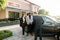 Successful multiethnical business people standing outdoors on the territory of car dealership. Young man manager showing
