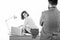 A successful office secretary. Young business secretary woman sitting on desktop against man boss. Company owner looking
