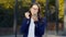 Successful pretty student woman looking to mirror and corrects her makeup with lipstick on office building background