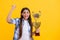 successful proud teen girl with champion cup award isolated on yellow