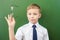 Successful schoolboy standing near the blackboard in school classroom