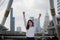 Successful young Asian business woman raising hands at urban building city background.