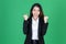 Successful young Asian business woman in suit raising hands and smiling on green isolated background