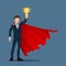 A successful young businessman in suit with smiley face, wear red cape raise up & holding a gold trophy cup. Winner or leader male