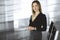 Successful young businesswoman is standing straight in a cabinet of a firm. Business headshot or portrait of a secretary